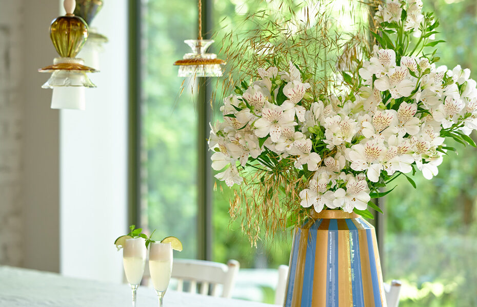 Witte Alstroemeria's in een kleurrijke vaas op een tafel in een lichte woonkamer.